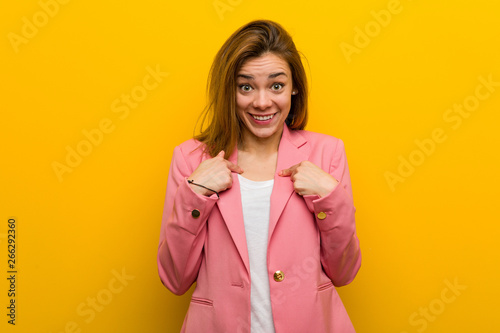 Young fashion business woman surprised pointing at herself, smiling broadly.