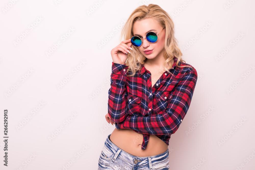 Cute amazed blonde girl tourist in shirt, holding her trendy glasses on white background