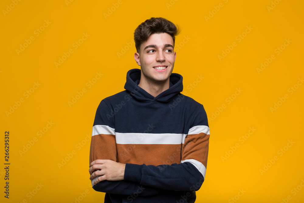 Young cool man wearing a hoodie smiling confident with crossed arms. - obrazy, fototapety, plakaty 