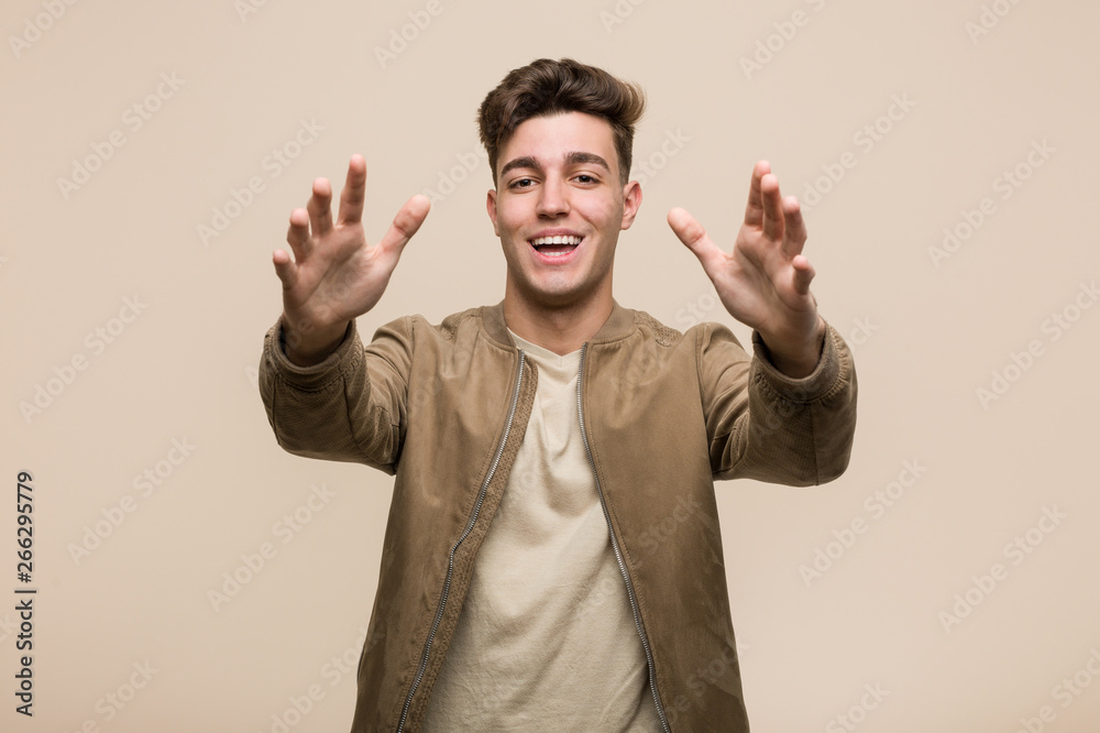 Fototapeta premium Young caucasian man wearing a brown jacket feels confident giving a hug to the camera.