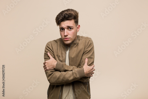 Young caucasian man wearing a brown jacket going cold due to low temperature or a sickness.