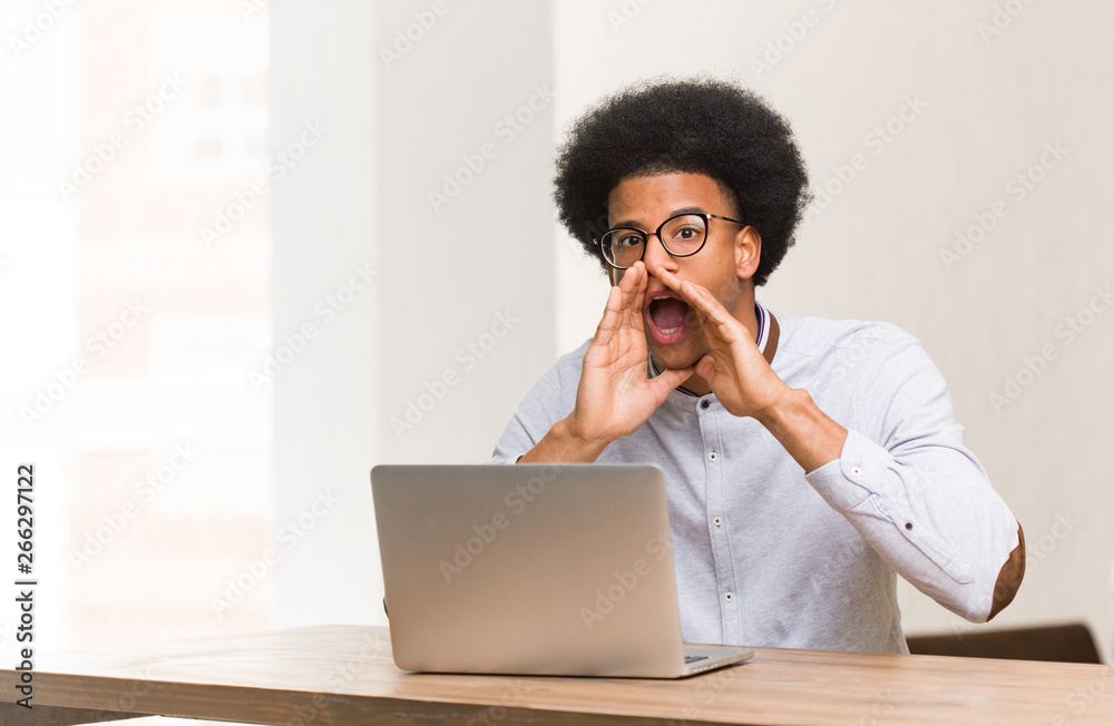Young black man using his laptop shouting something happy to the front