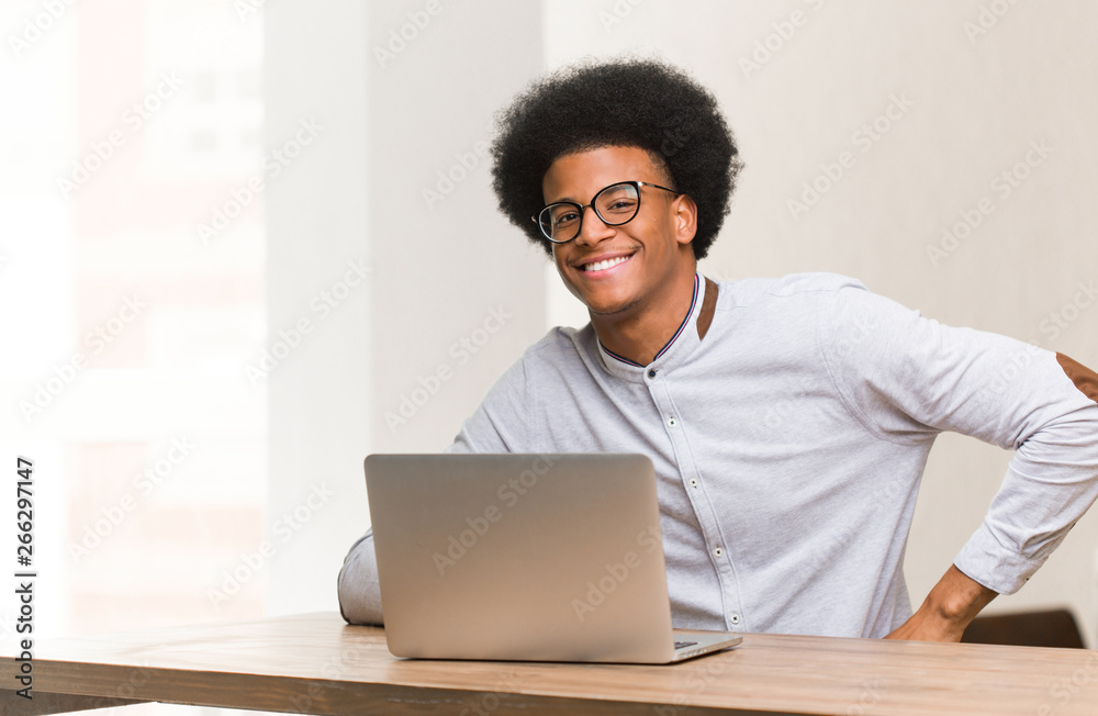Young black man using his laptop with hands on hips Young black man using his laptop with hands on hips