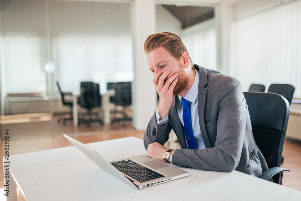 Stressed redhead businessman looking at laptop screen at work. Stressed redhead businessman looking at laptop screen at work.