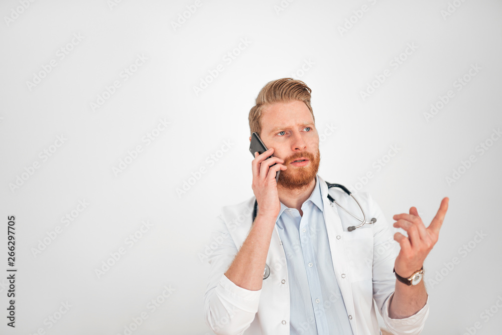 Serious ginger doctor talking on mobile phone, copy space. Serious ginger doctor talking on mobile phone, copy space.