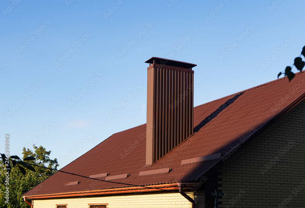Profiled sheeting chimney on the metal tile roof with rain gutters and snow guards