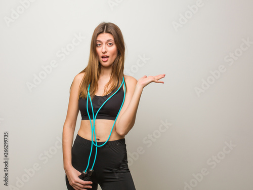 Young fitness russian woman holding something on palm hand. Holding a jump rope.