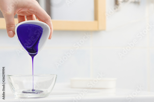 Woman pouring purple hair dye or shampoo