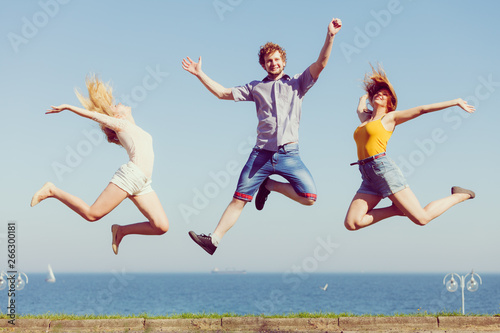 Group of friends boy two girls jumping outdoor