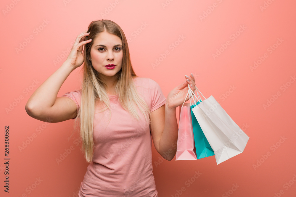 Young pretty russian girl worried and overwhelmed. She is holding a shopping bags. Young pretty russian girl worried and overwhelmed. She is holding a shopping bags.