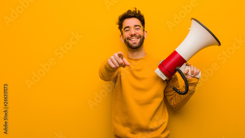 Young man holding a megaphone cheerful and smiling photo