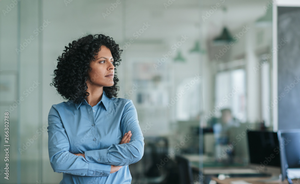 Focused young businesswoman standing alone in an office - obrazy, fototapety, plakaty 