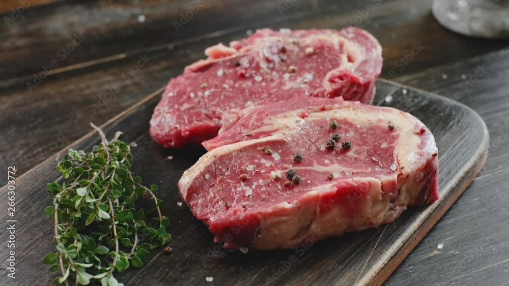 two raw marbled beef steaks in olive oil and spices ready for frying. dinner party concept two raw marbled beef steaks in olive oil and spices ready for frying. dinner party concept