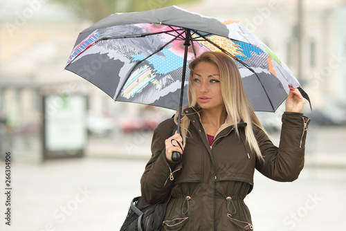 Attractive young elegant girl walking in the park with umbrella, autumn day