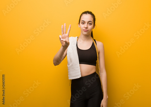 Young fitness girl showing number three