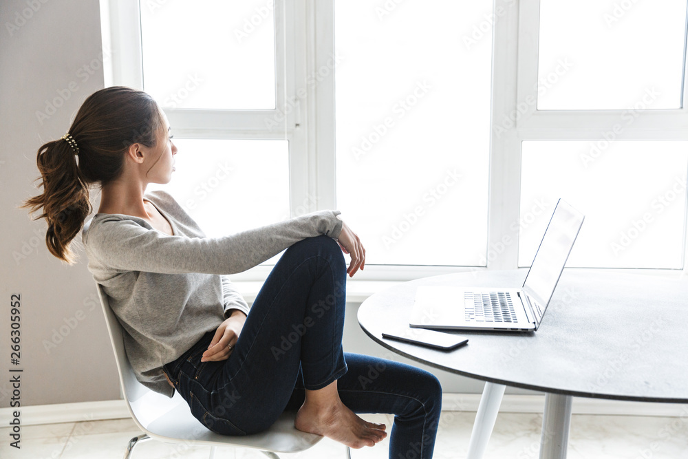 Attractive smiling young woman working on laptop