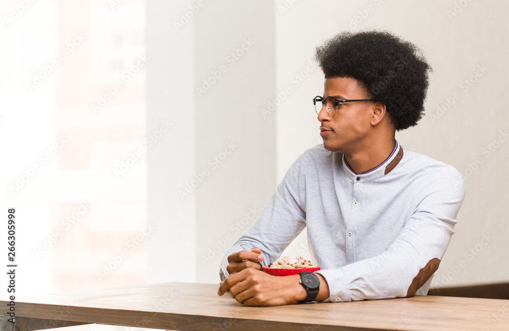 Young black man having a breakfast on the side looking to front Young black man having a breakfast on the side looking to front