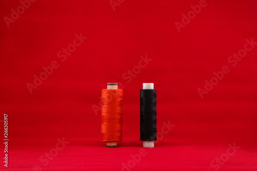 Threads, black scissors with white buttons on a red background