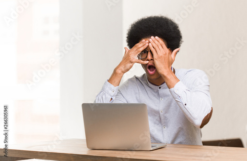 Young black man using his laptop feels worried and scared