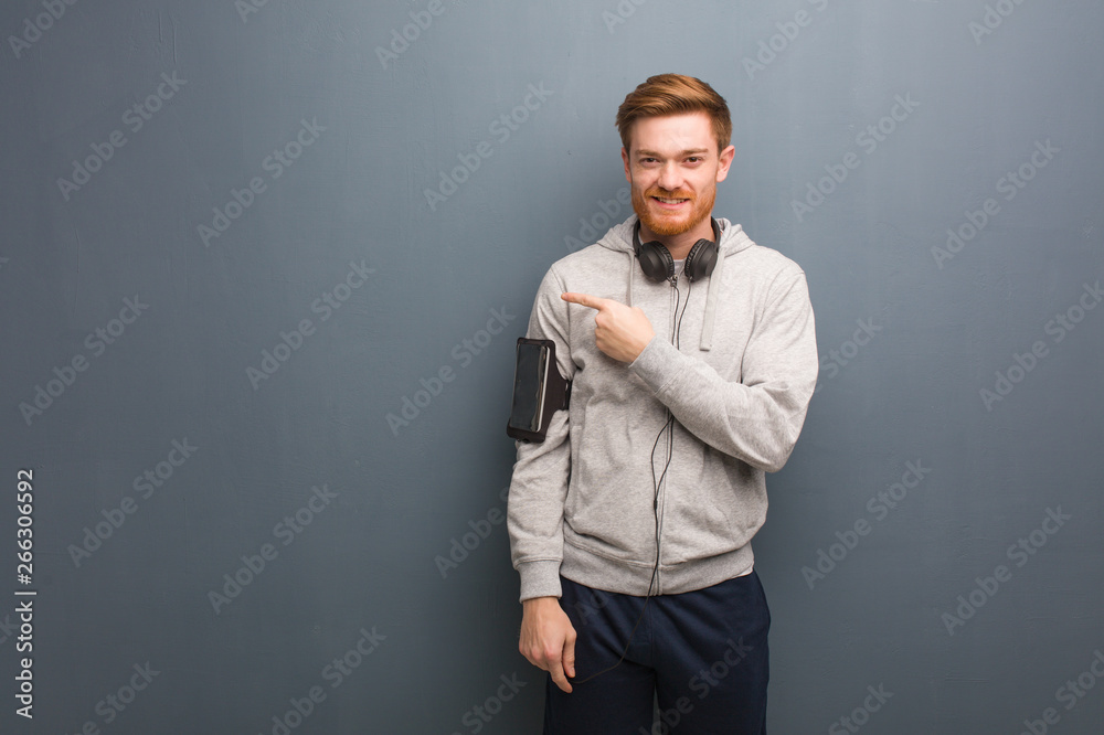 Young fitness redhead man smiling and pointing to the side Young fitness redhead man smiling and pointing to the side
