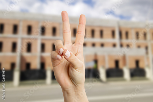 Woman making victory or peace sign in front of building © Thunderstock
