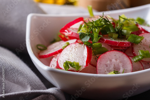 Radish salad in a white bowl on a dark background
