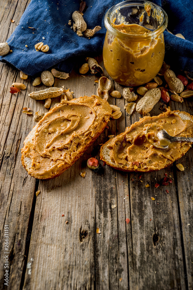 Fototapeta premium Little peanut butter jar with crunchy peanut butter sandwiches on rustic wooden table