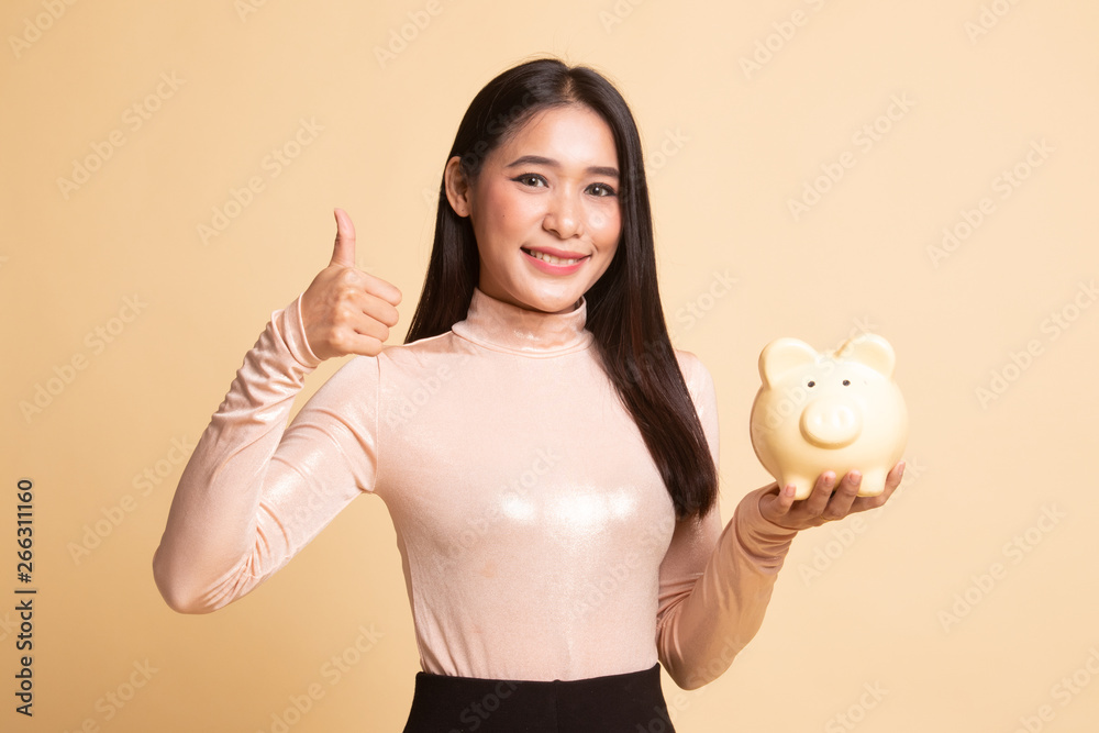 Asian woman thumbs up with pig coin bank. Asian woman thumbs up with pig coin bank.