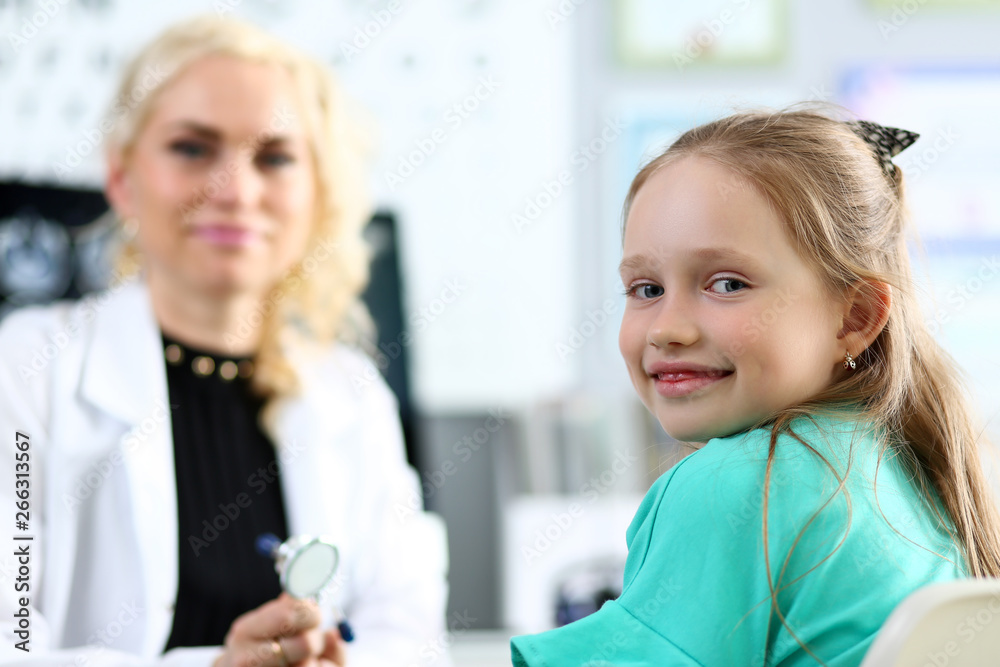 Cute smiling little girl portrait with female doctor in background Cute smiling little girl portrait with female doctor in background