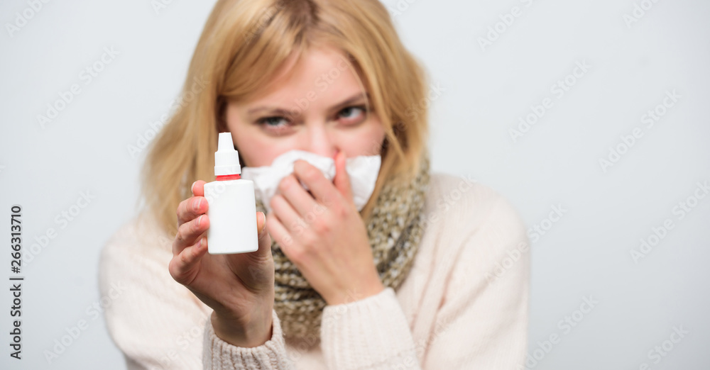 Finding relief just a spray away. Sick woman spraying medication into nose. Ill girl with runny nose using nasal spray. Cute woman nursing nasal cold or allergy. Treating cold or allergic rhinitis Finding relief just a spray away. Sick woman spraying medication into nose. Ill girl with runny nose using nasal spray. Cute woman nursing nasal cold or allergy. Treating cold or allergic rhinitis