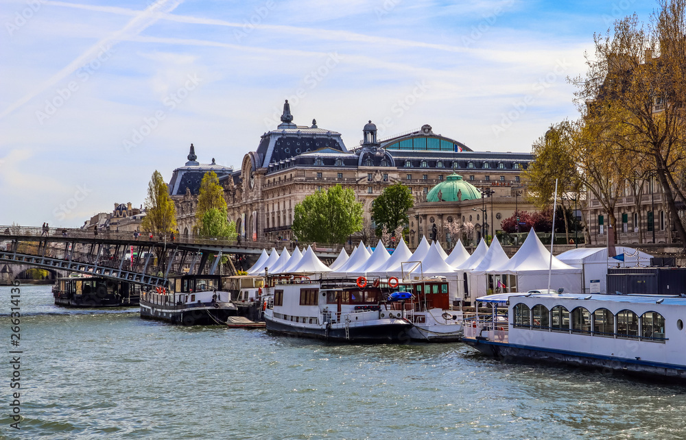 Fototapeta premium Pedestrian bridge (Passerelle Léopold-Sédar-Senghor) over Seine river, boats and historic buildings of Paris France