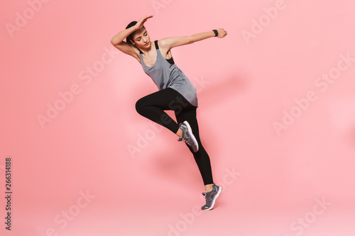 Amazing beautiful young pretty fitness woman running make sport exercises isolated over pink wall background.