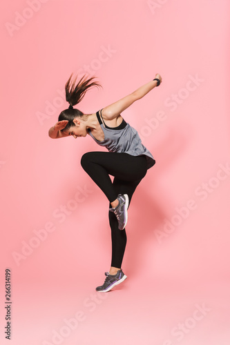 Beautiful young pretty fitness woman running make sport exercises isolated over pink wall background.