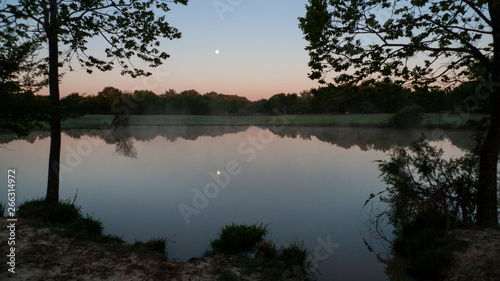 Full moon at daybreak, still waters with reflections