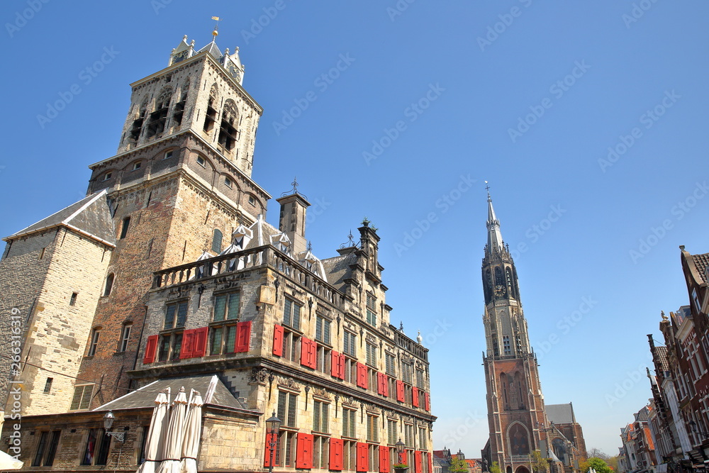 The external facade of the Town Hall (rebuilt in 1629) on the left and the clock tower of Nieuwe Kerk on the right, Delft, Netherlands