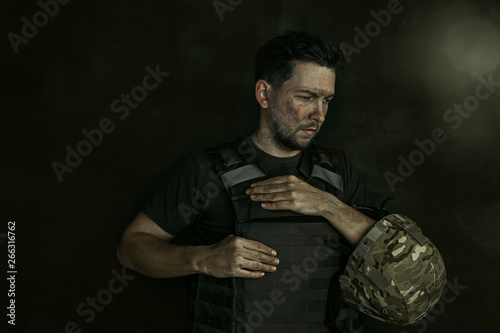 Have no heart, but it hurts. Close up portrait of young male soldier. Man in military uniform on the war. Depressed and having problems with mental health and emotions, PTSD, rehabilitation.