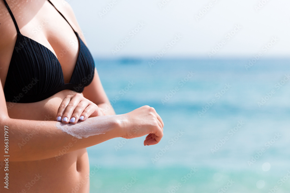 Pretty girl is putting sun lotion on her hand at the beach Pretty girl is putting sun lotion on her hand at the beach