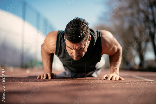Fitness man doing push ups outdoor. Athlete training.
