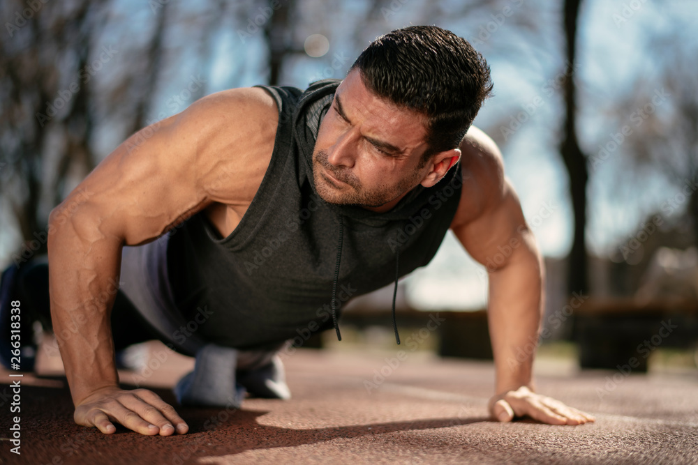 Obraz premium Fitness man doing push ups outdoor. Athlete training.