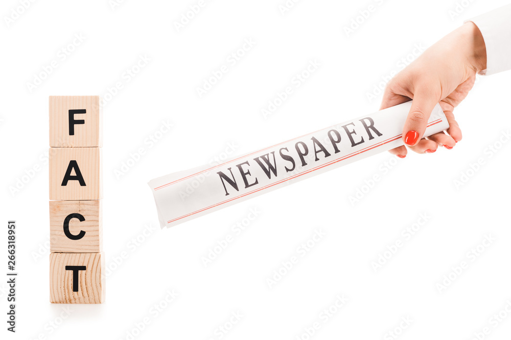 Obraz premium cropped view of woman holding newspaper near wooden blocks with fact lettering isolated on white
