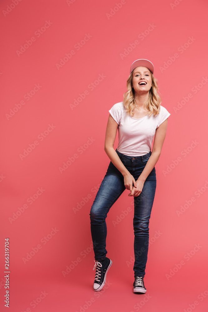 Full length portrait of young blond woman 20s wearing casual jeans and sneakers smiling at camera Full length portrait of young blond woman 20s wearing casual jeans and sneakers smiling at camera