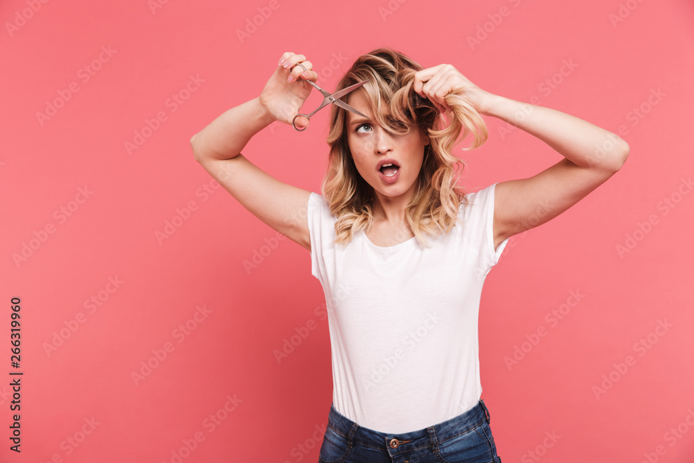 Portrait of caucasian blond woman 20s wearing casual t-shirt cutting her hair with scissors Portrait of caucasian blond woman 20s wearing casual t-shirt cutting her hair with scissors