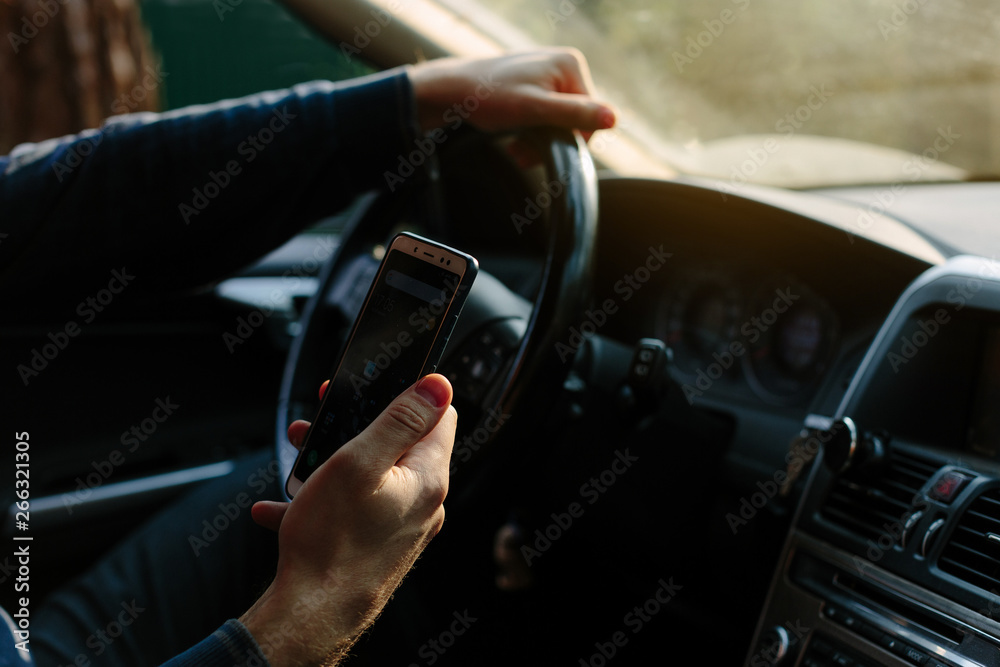 man sits in the car looks into the phone