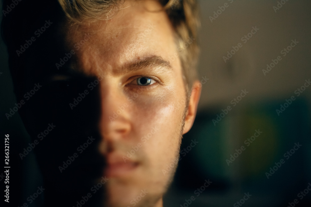 Serious man portrait in light on dark background. Closeup of man face with blue eyes and blonde hair in softlight. Selective focus. Creative image Serious man portrait in light on dark background. Closeup of man face with blue eyes and blonde hair in softlight. Selective focus. Creative image