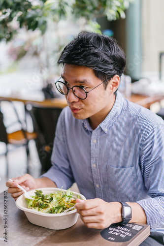 Mid shot of a good looking, confident Asian Korean businessman having a lunch meeting with his colleague in a restaurant in Asia during the day. He is professionally dressed in polo and pants.