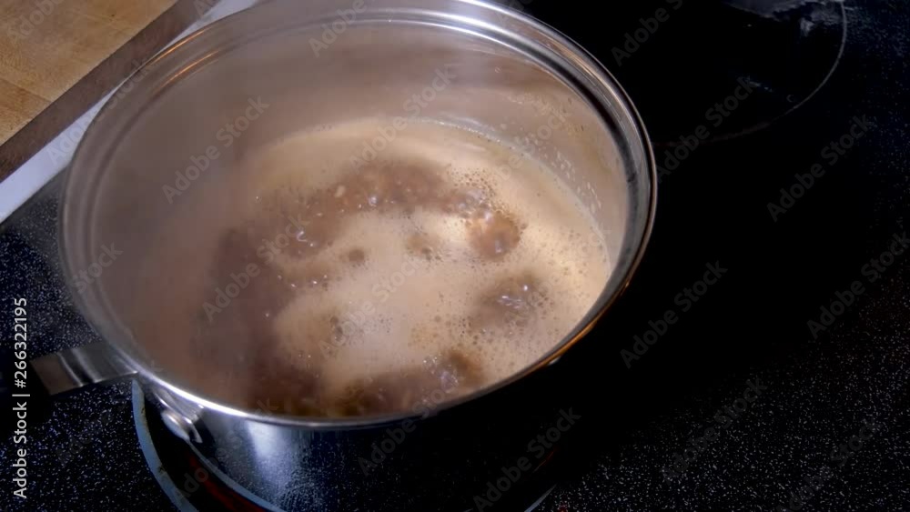 Rice boiling in a beef broth in a pan on stove Rice boiling in a beef broth in a pan on stove