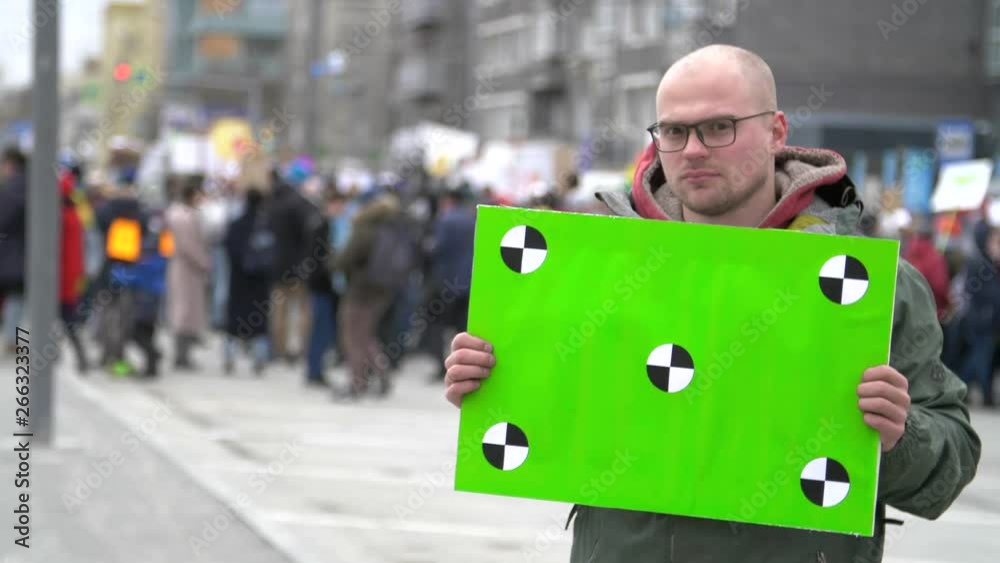 MOSCOW, RUSSIA - WINTER: Green banner in hands protester. Sad man with a poster in hands. 20s caucasian boy. Crowd people in the background on street. People protesting in Moscow 