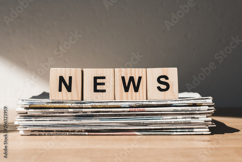 wooden blocks with news lettering on pile of print newspapers photo