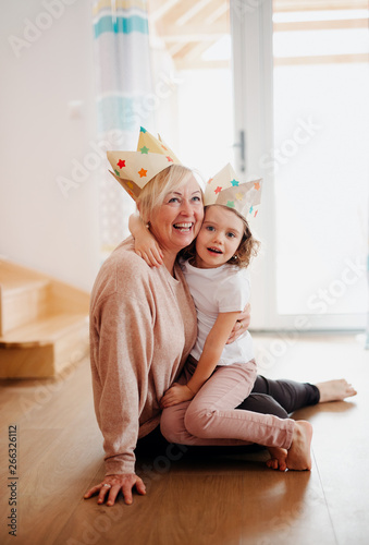 Fotografía A portrait of small girl with grandmother hugging at home.