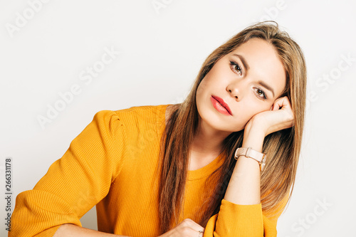 Studio shot of beautiful young woman with blond hair, wearin yellow pullover, posing on white background photo